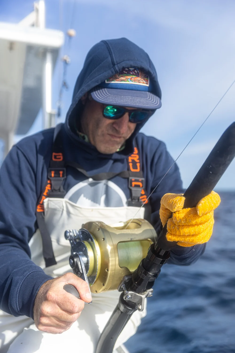 A fisherman working a rod and reel aboard his fishing boat